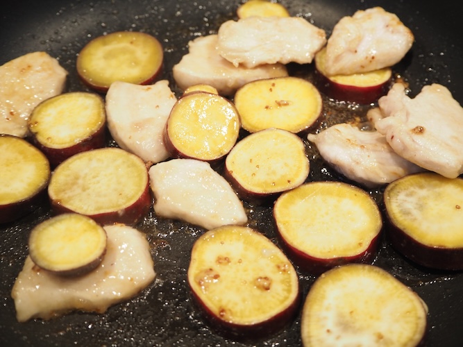 鶏むね肉に焼き色がついたら裏返し、さつまいもと混ぜ合わせた調味液を回しいれて炒める。