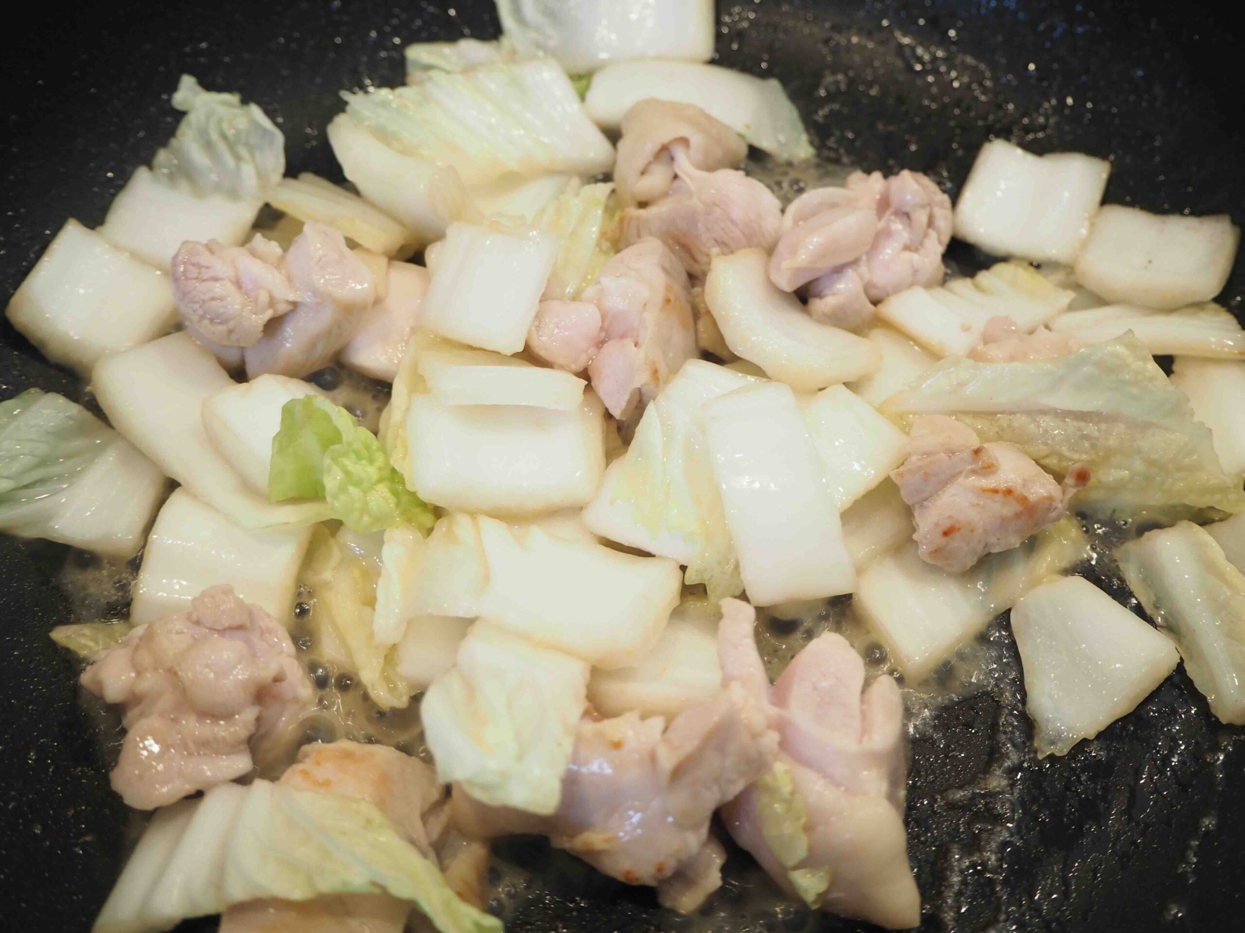 鶏もも肉に焼き色がついたら、白菜の白い部分を入れて炒める。