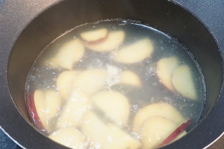 鍋に【調味料】の塩 小さじ1/2、鶏ガラスープの素 小さじ1/2、おろししょうが 小さじ1/3、水 400ccさつまいもを入れて中火で熱し、煮立ったらふたをして弱火で2分ほど煮る。