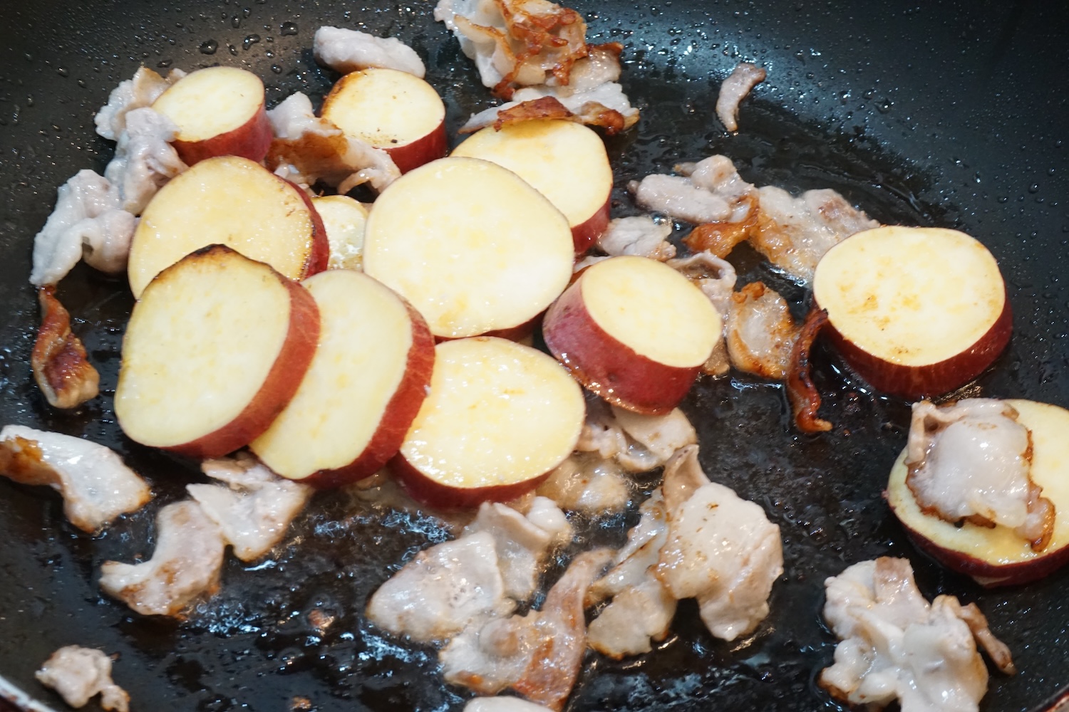 豚バラ肉に焼色がついたら、さつまいもを入れて炒める。