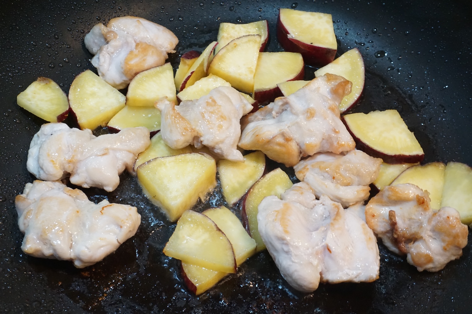 皮目が焼けたら鶏もも肉をひっくり返し、水気を切ったさつまいもを加えて火を通す。