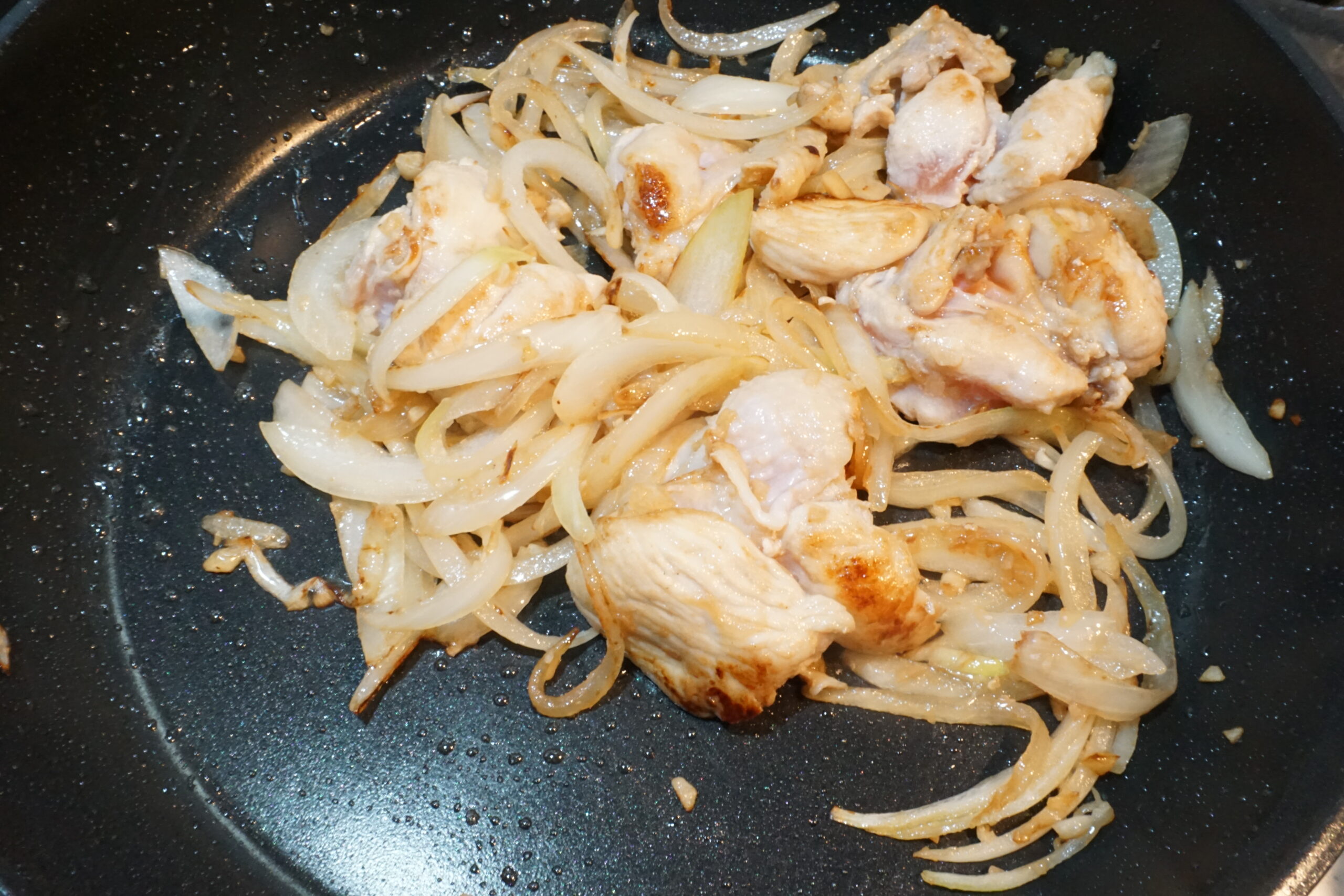 にんにくの香りが立ったら切った玉ねぎと鶏もも肉を入れて炒める。